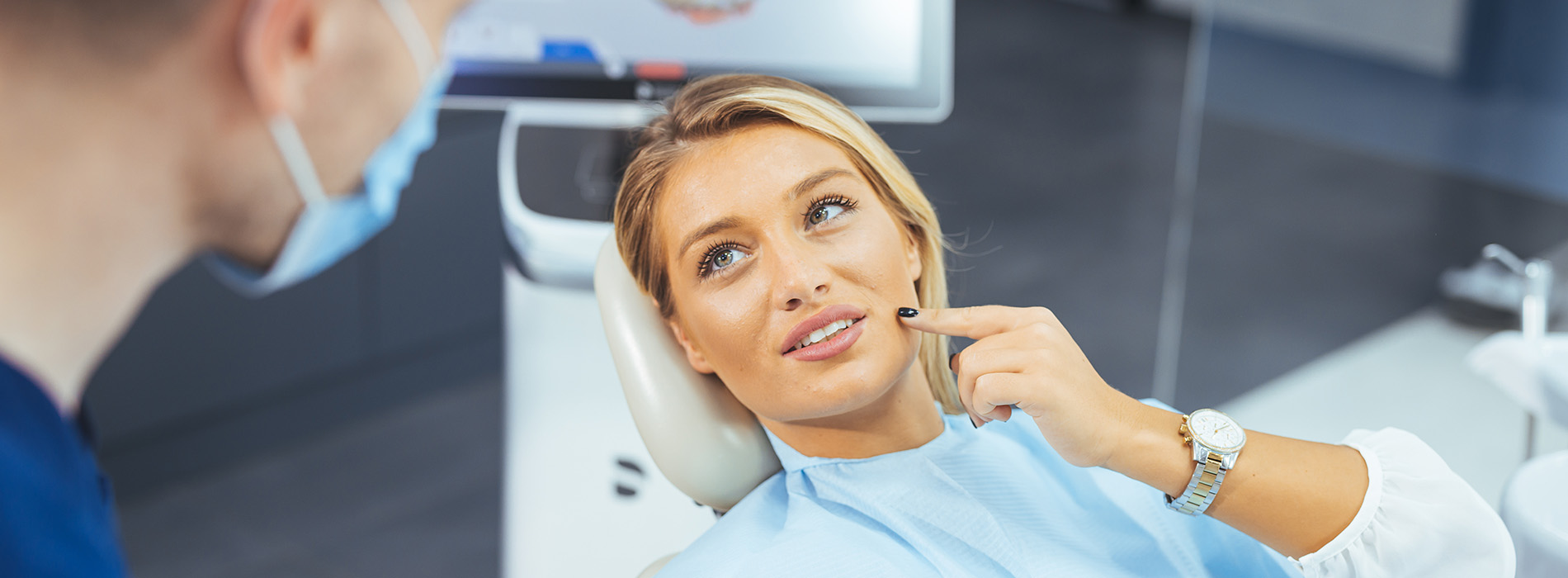 A well-lit reception area with a desk, computer monitor, and potted plant.