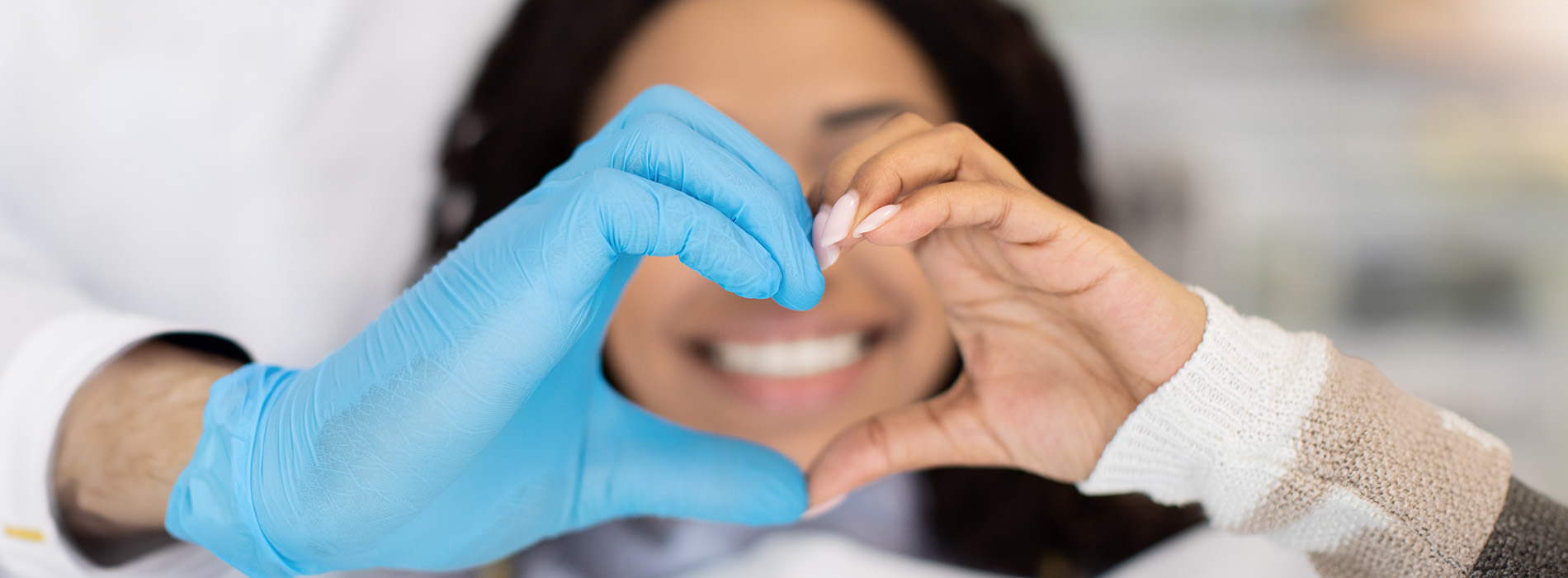 The image shows a group of people, possibly professionals given their attire and the setting that appears to be an office or professional environment. They are gathered around a table with a laptop on it, engaged in what seems to be a discussion or meeting.