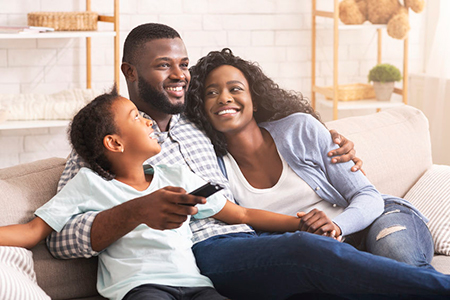 A happy family of four, with a man, woman, and two children, sitting together on a couch, smiling and enjoying each other s company.