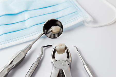 The image displays a collection of dental instruments, including a toothbrush with toothpaste on its bristles, placed on a blue cloth, which appears to be a sterilization cloth, along with other dental equipment such as tweezers and scissors.